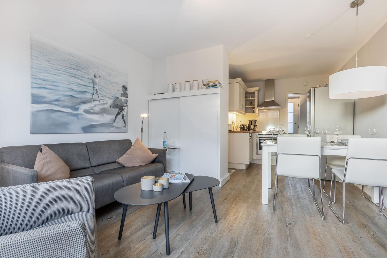 Wohn- und Essbereich mit Küche. Sofa, Tisch und Stühle sind sichtbar.