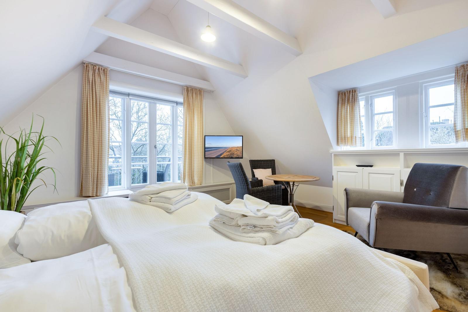 Schlafzimmer mit Dachschräge, Bett, TV und Sitzgelegenheiten