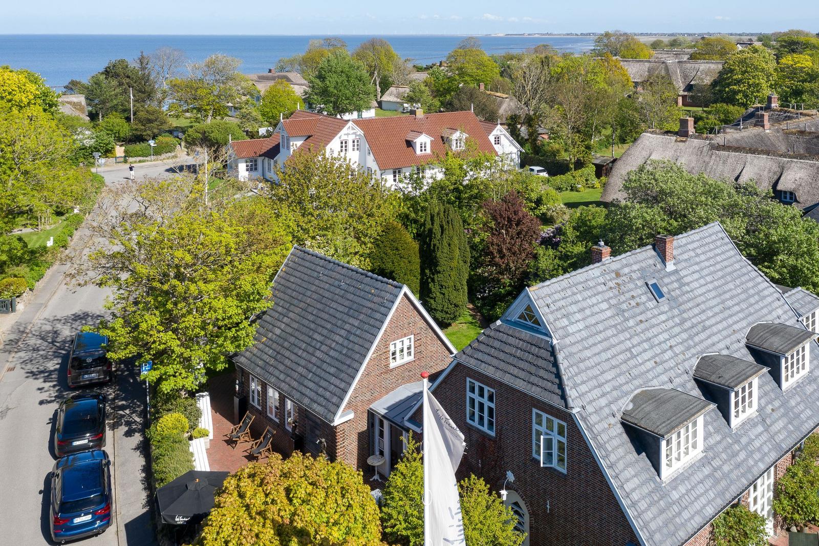 Haus mit Dachgauben und Garten, Blick aufs Meer und umliegende Häuser.