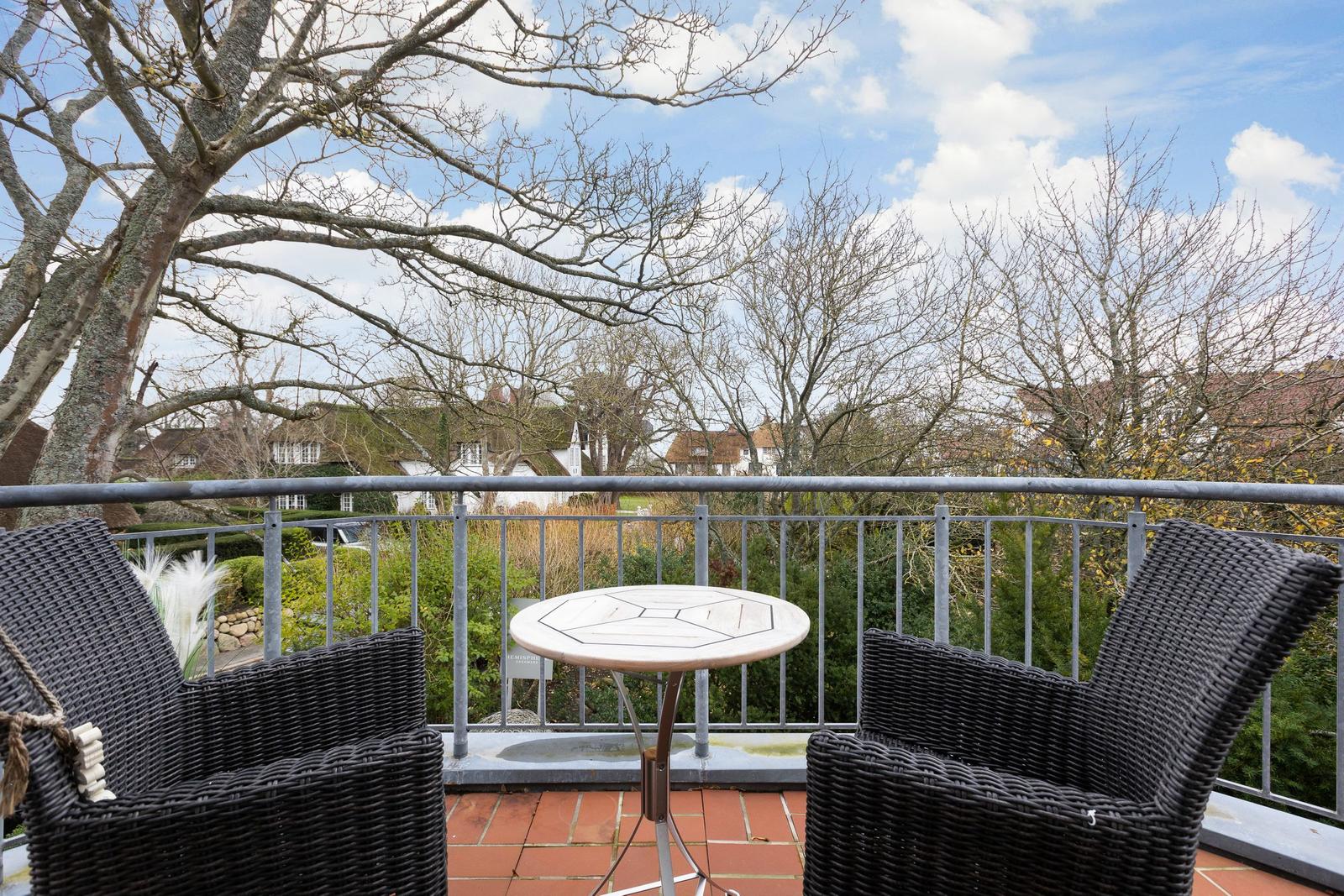 Terrasse mit zwei Stühlen und Tisch, Blick auf Bäume und Häuser
