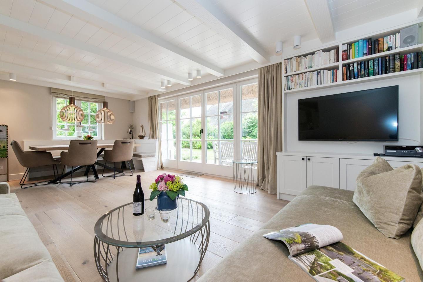 Living and dining area with TV, bookshelf, and garden view