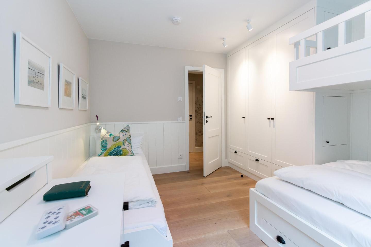 Room with two beds, closet, and wooden floor.