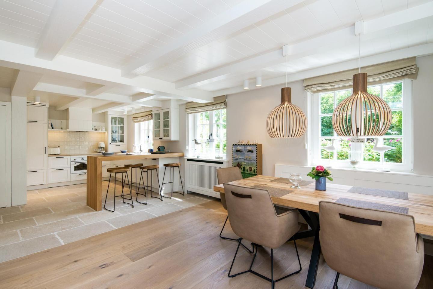 Kitchen and dining area with wooden table, chairs, and hanging lamps.