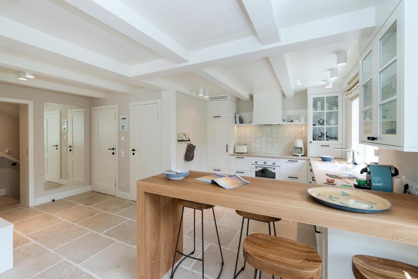 Kitchen with wooden island, white cabinets, stone floor