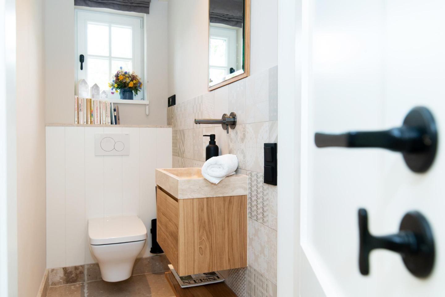 Bathroom with sink, toilet, and window with flowers.