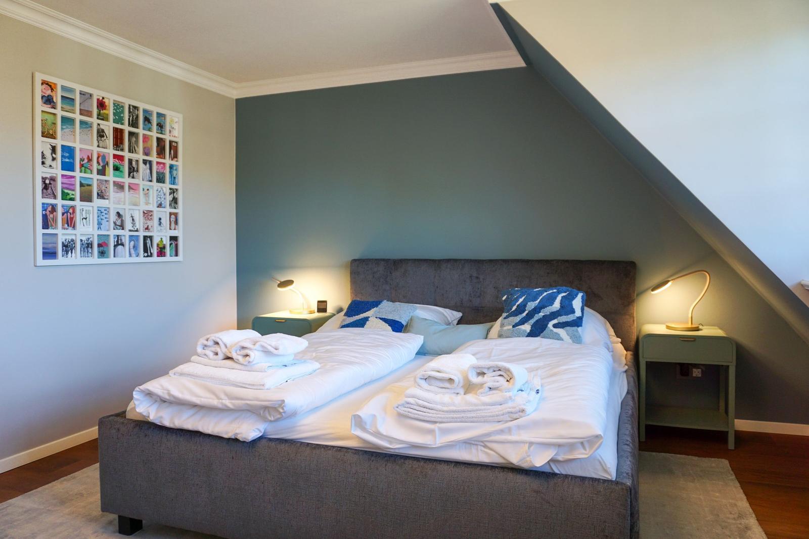 Schlafzimmer mit Doppelbett, zwei Nachttischen und Wandbild.