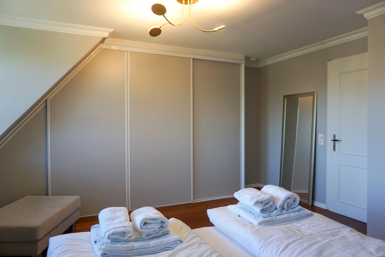Schlafzimmer mit Bett, Kleiderschrank und Spiegel.