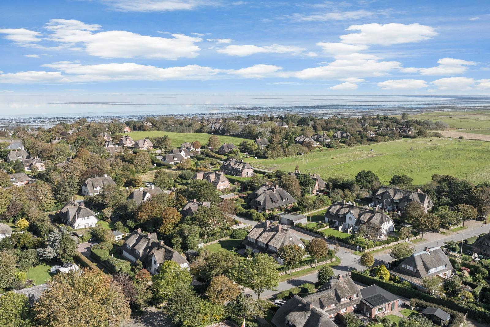 Dorf mit Strohdächern, Grünflächen und Blick auf die Nordsee.
