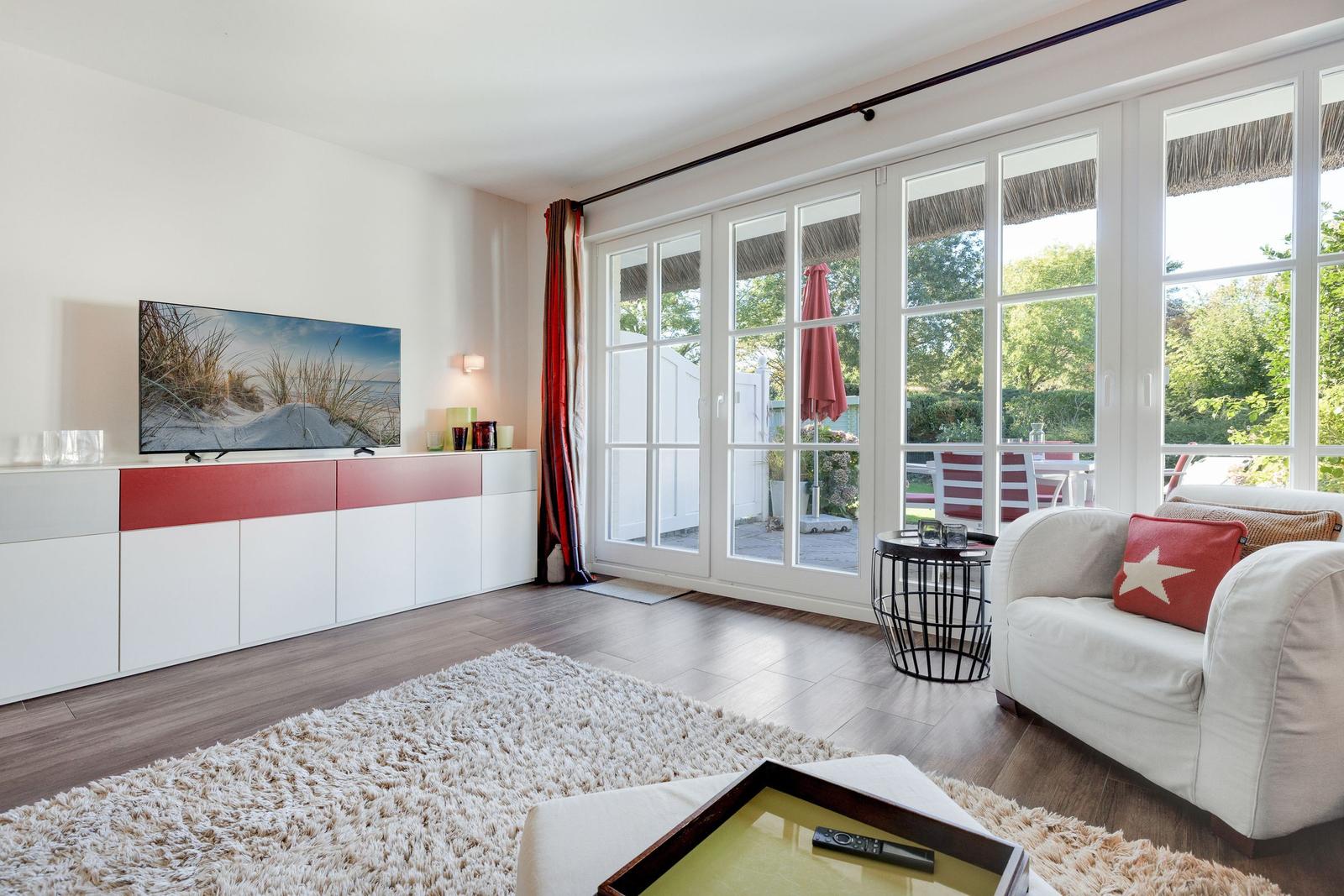 Wohnzimmer mit Fernseher, Sofa und Blick auf Terrasse
