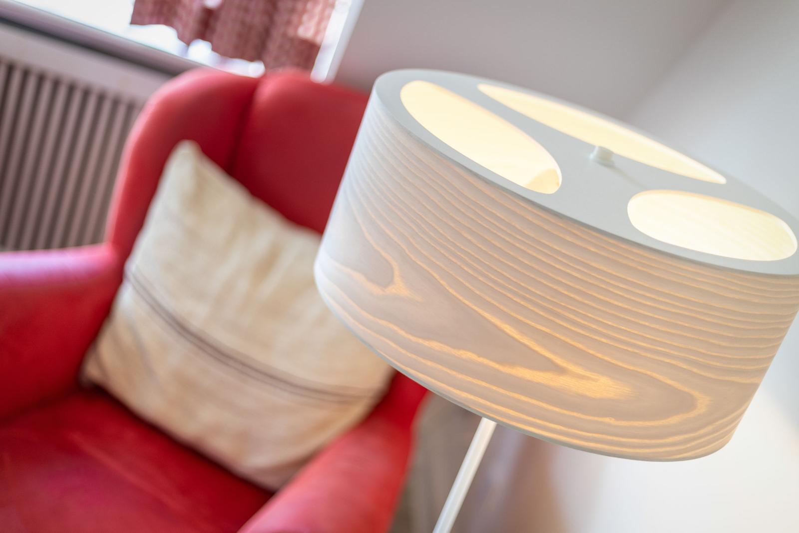 Rote Sitzgelegenheit mit Kissen und beleuchteter Stehlampe.