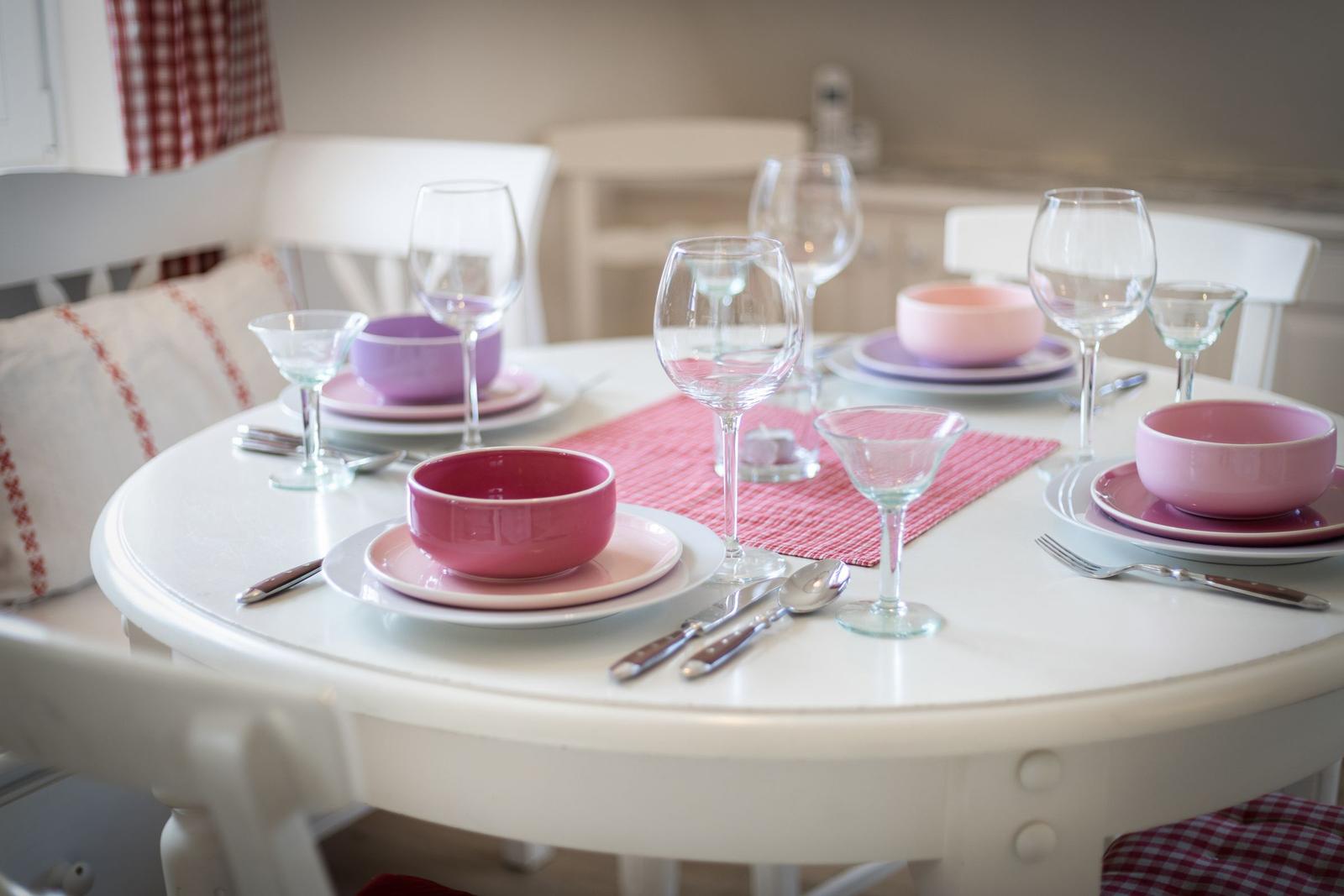 Runde weiße Tischplatte mit rosa Geschirr und Gläsern.