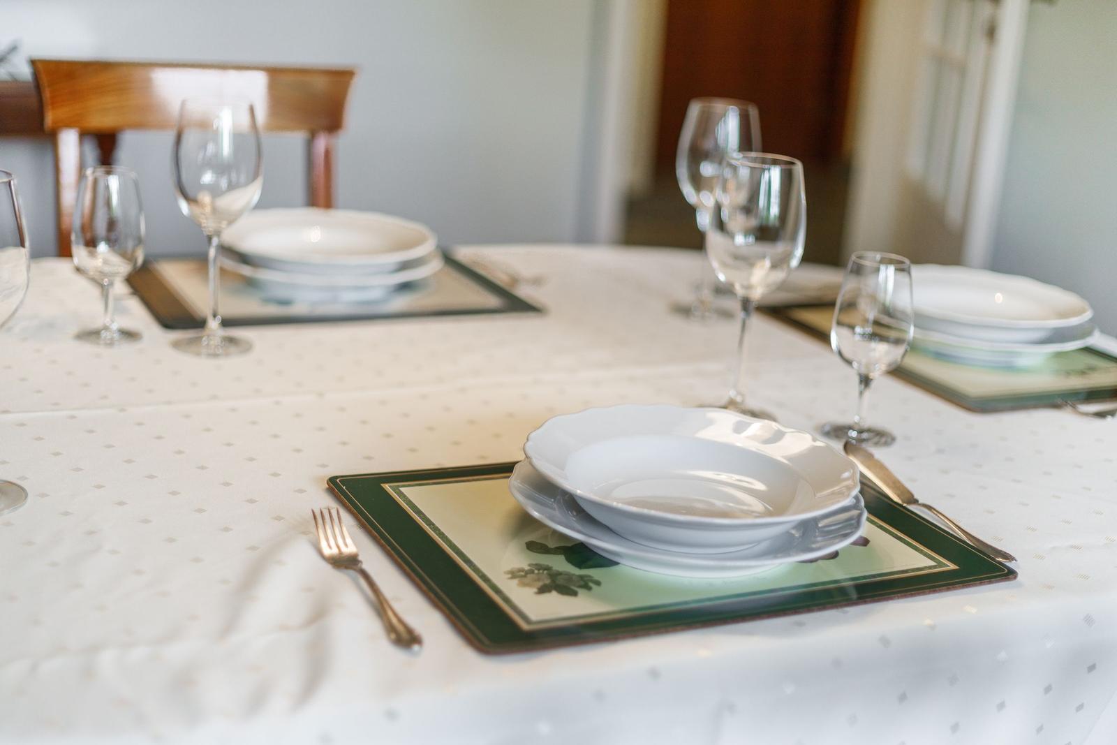 Table set with plates, glasses, and cutlery on tablecloth.