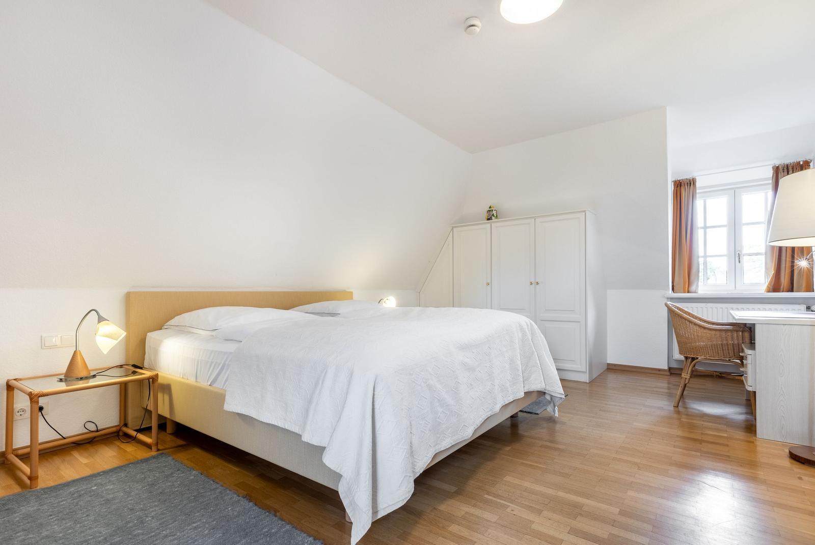 Bedroom with double bed, wardrobe, and desk.