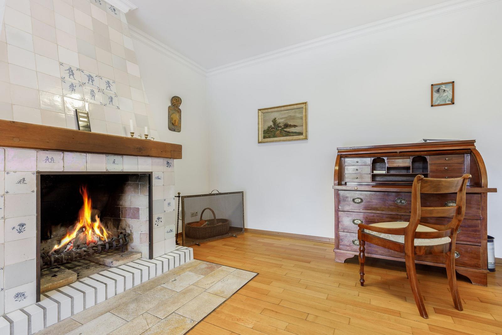 Room with fireplace, hardwood floor, and writing desk furniture.