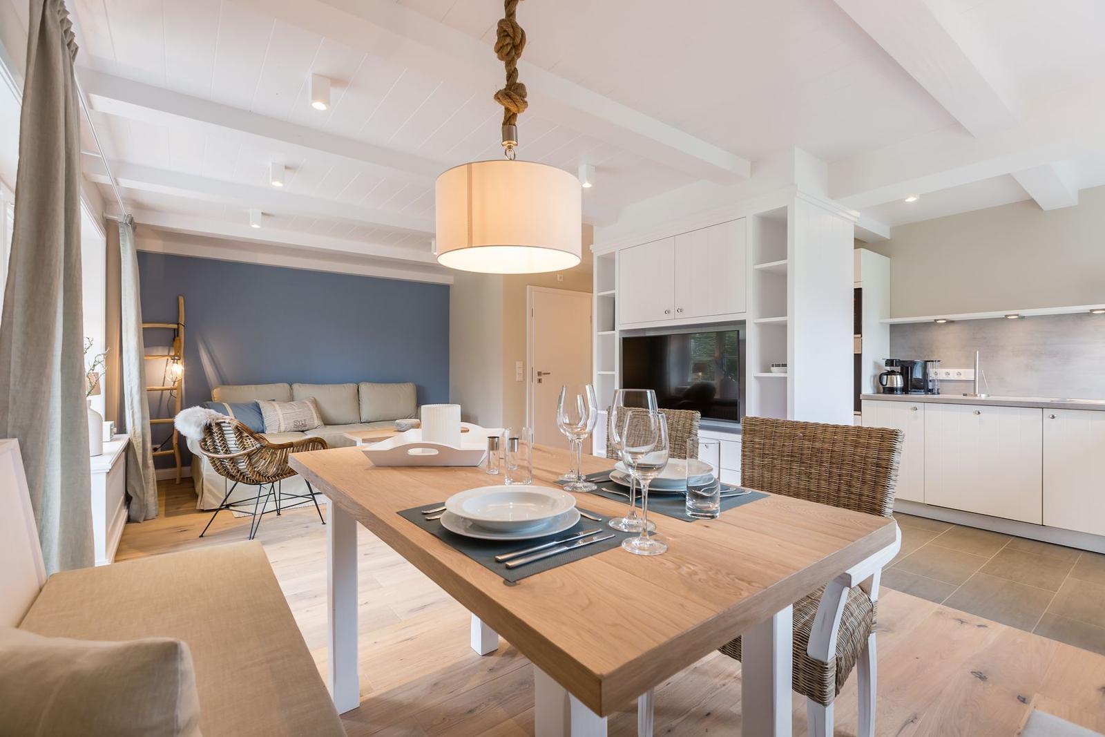 Dining area with table and chairs. Kitchen and living area in background.