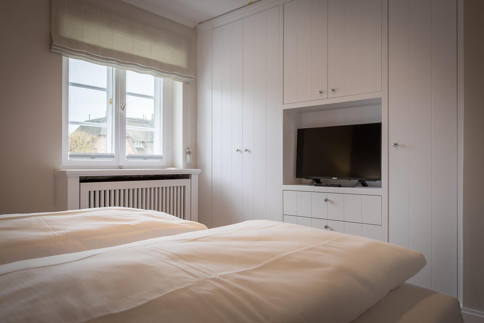 Bedroom with double bed, window, and built-in TV.