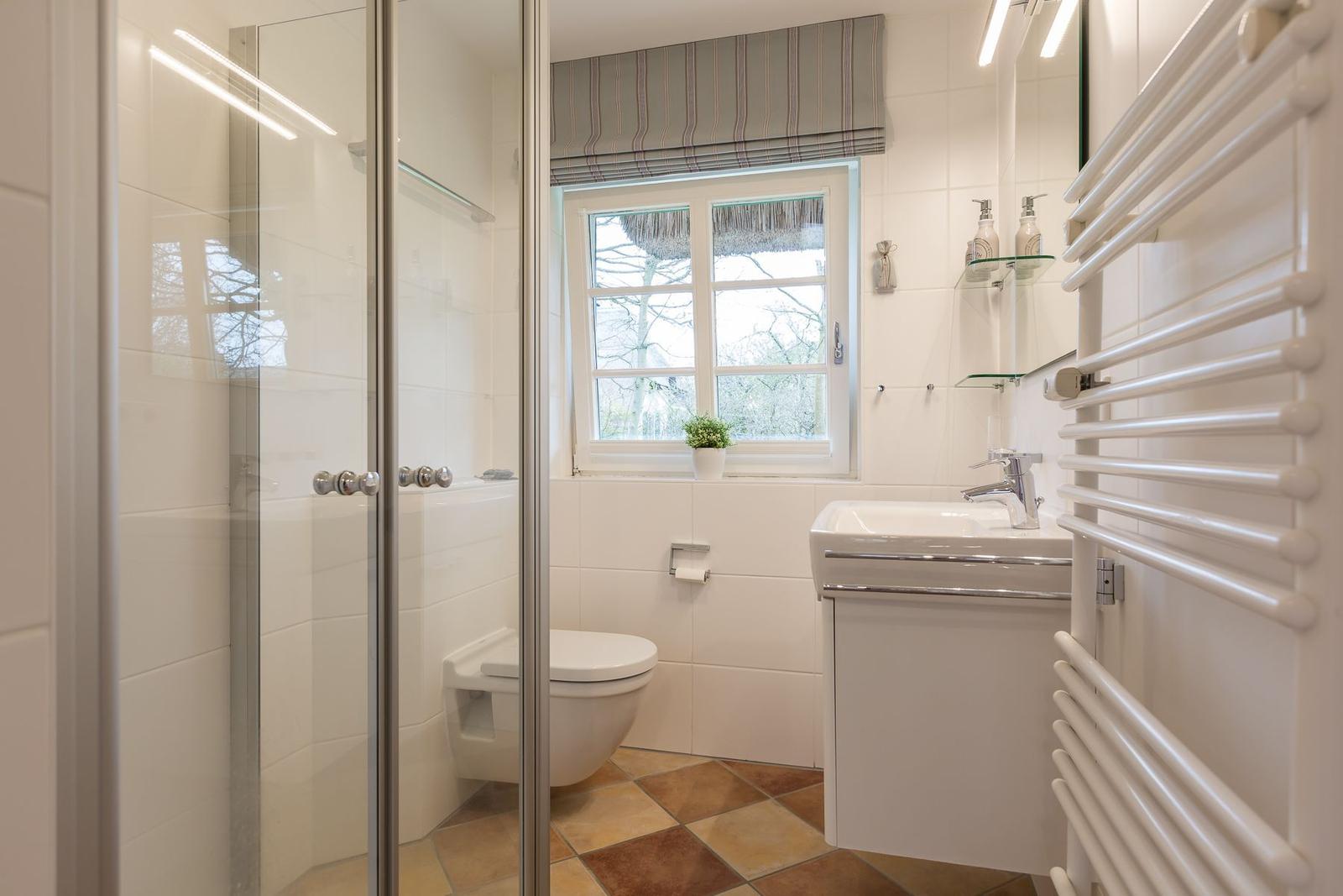 Bathroom with shower, toilet, sink, and window.