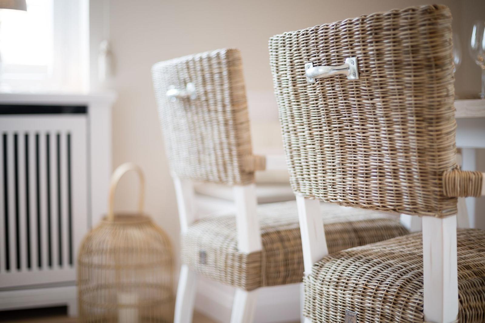 Two wicker chairs with white legs are at a table.