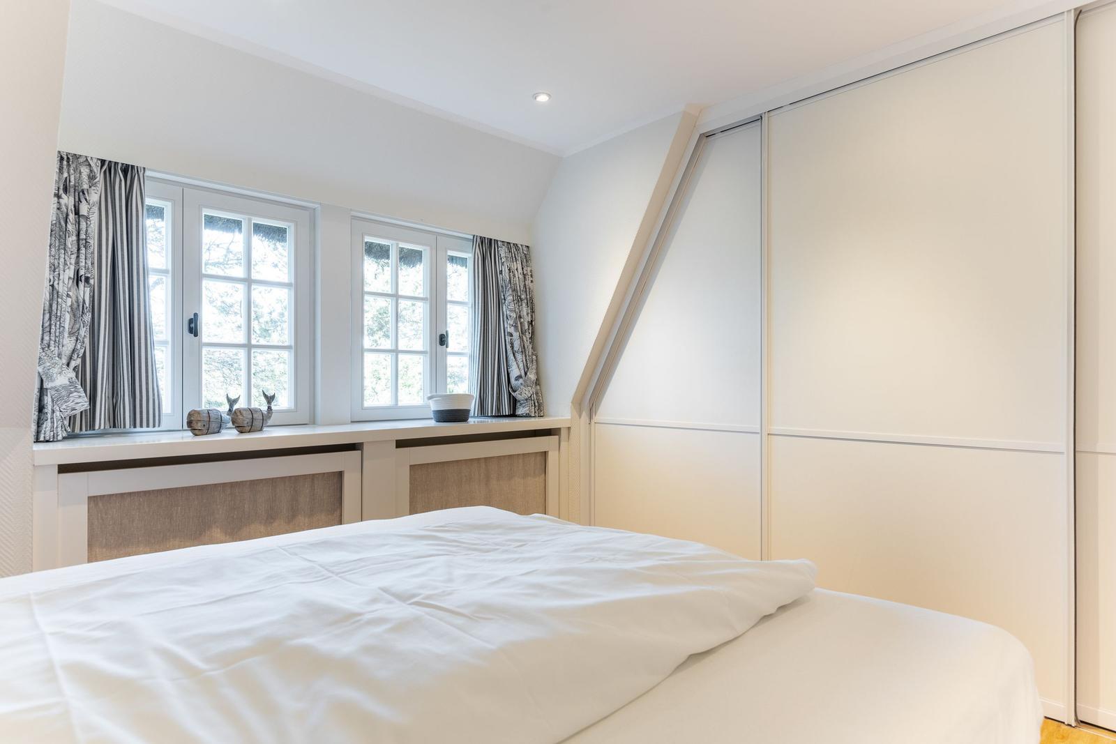 Schlafzimmer mit Dachschrägen, Fenstern und Schlafplatz.