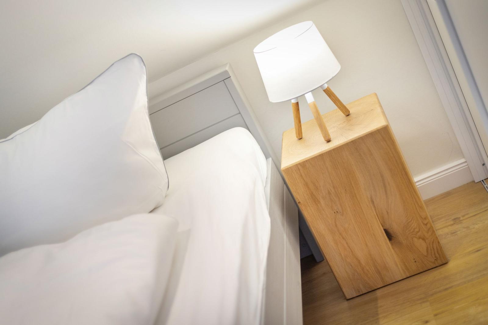 Schlafzimmer mit Bett, Nachttisch und Lampe.
