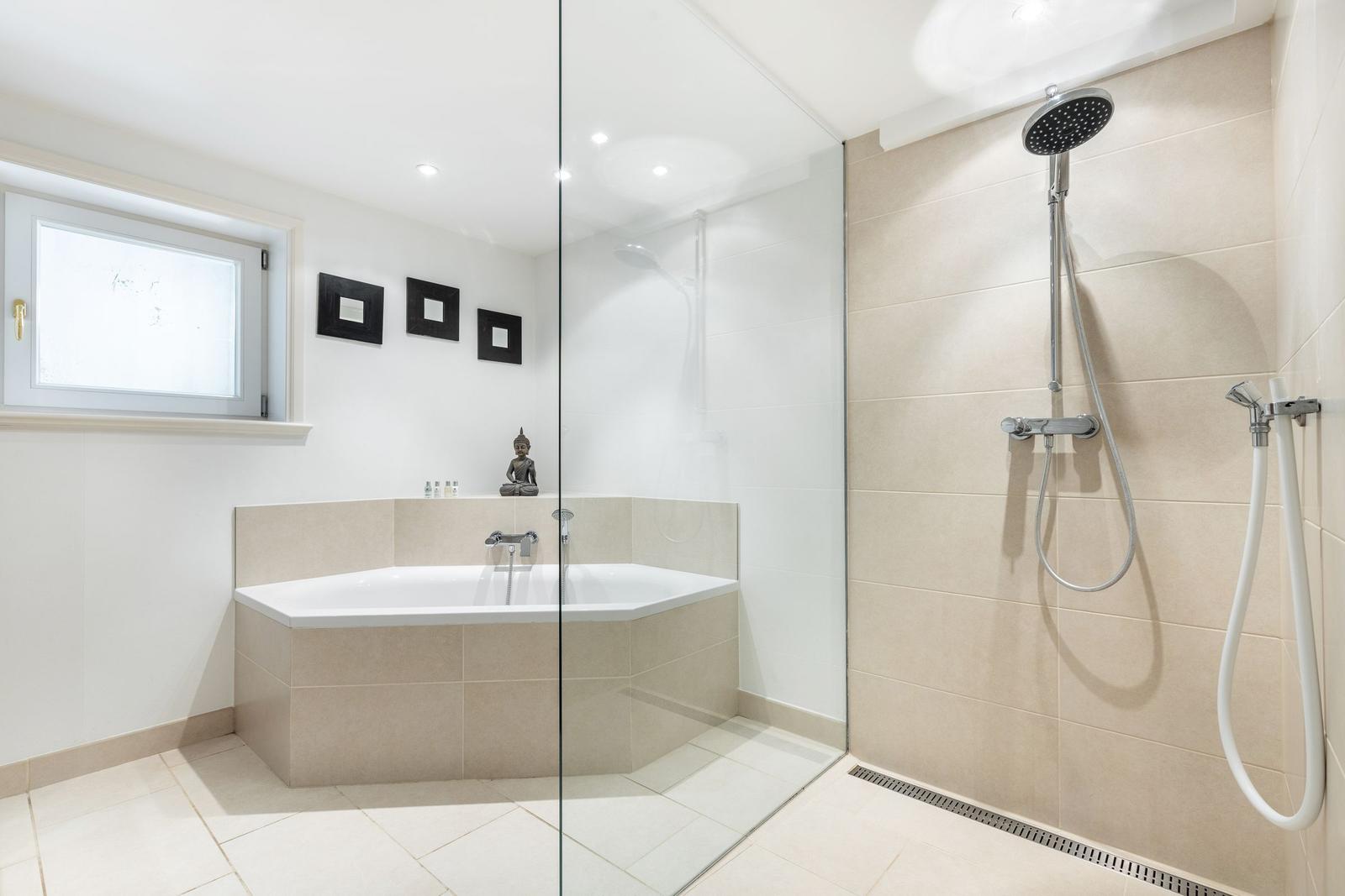Bad mit Dusche und Badewanne, Fenster und Buddha-Statue