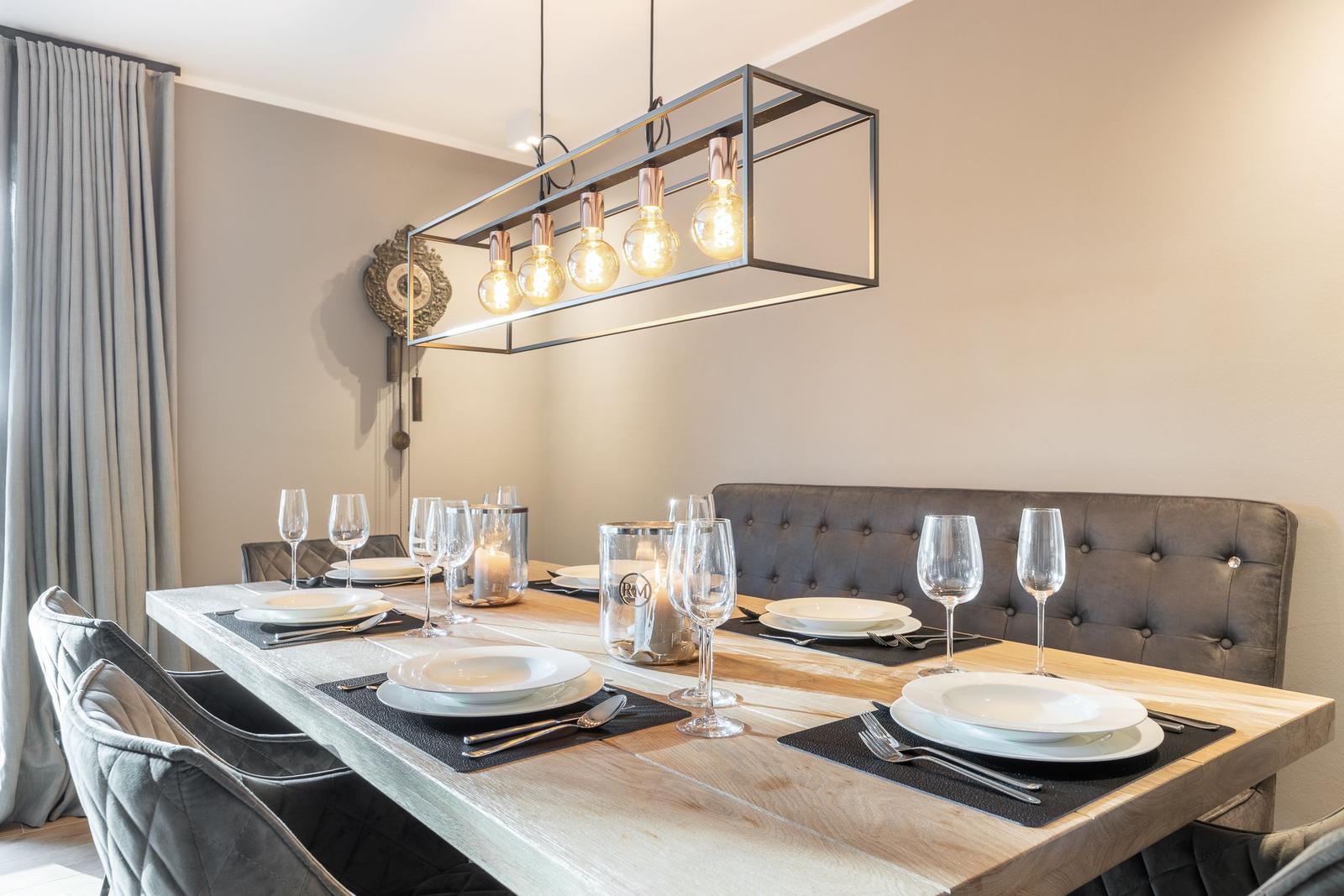 Esszimmer mit Holztisch, grauen Stühlen und moderner Deckenleuchte.