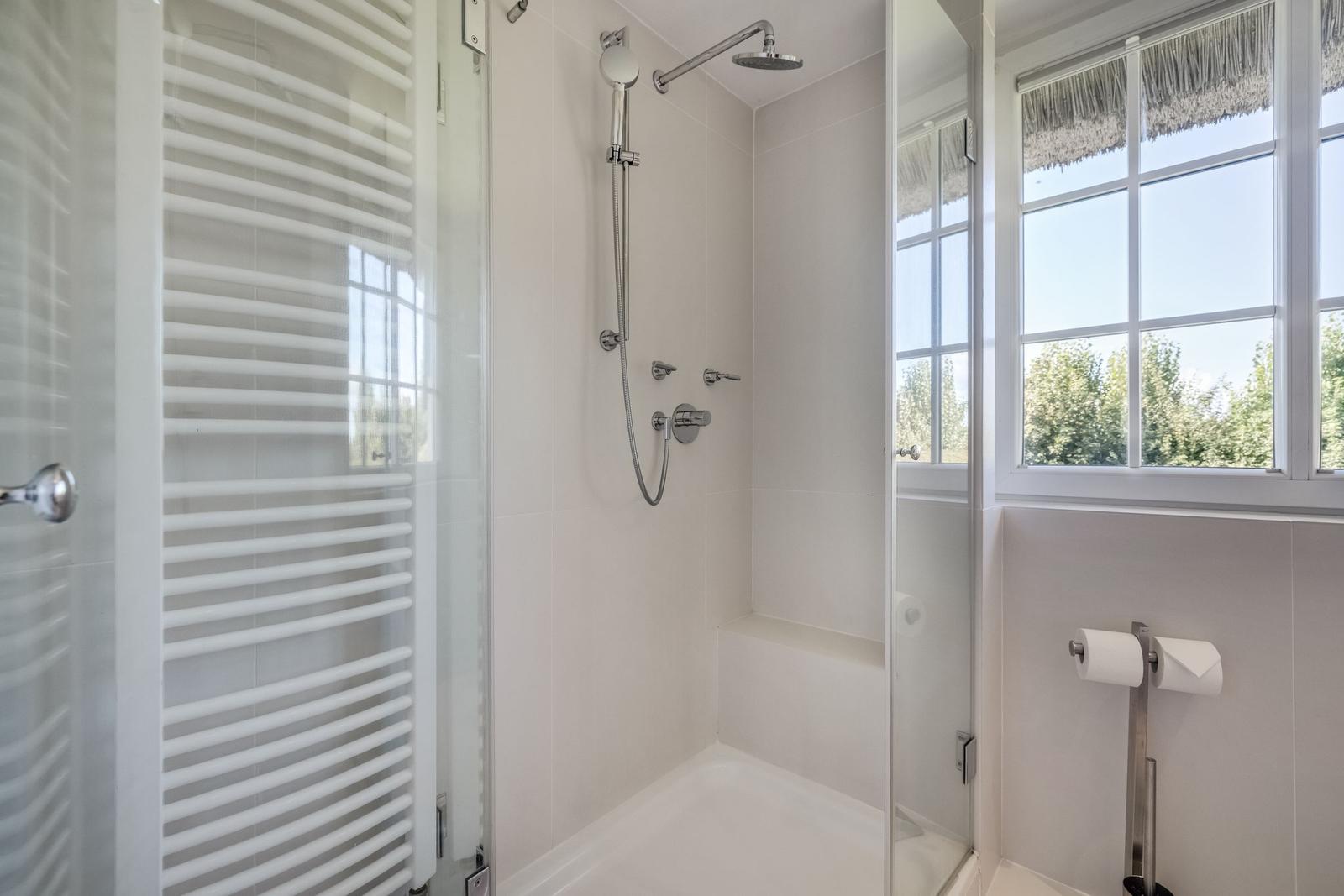 Shower cabin with showerhead, window, and heater.
