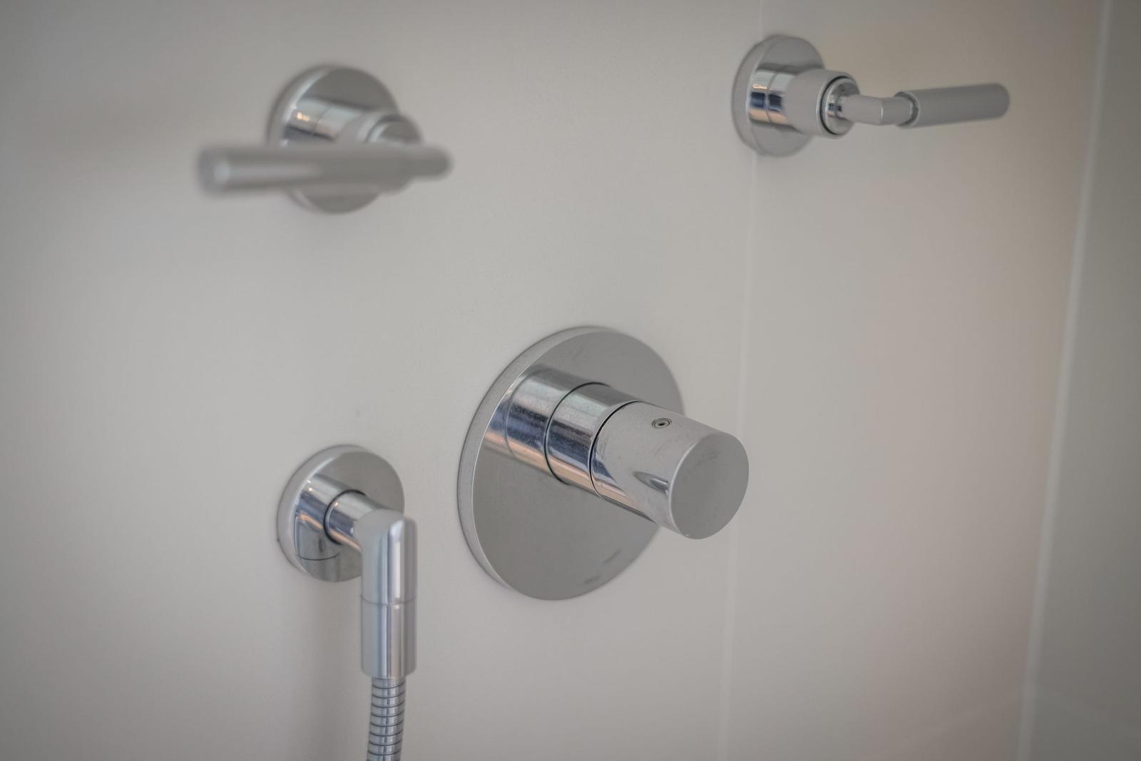 Showerhead with rotary control and two levers on white wall
