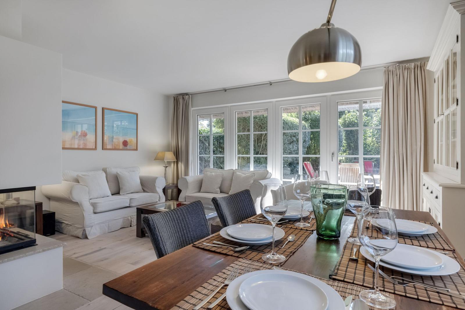Dining area with table and chairs, view of living area with sofa and fireplace.