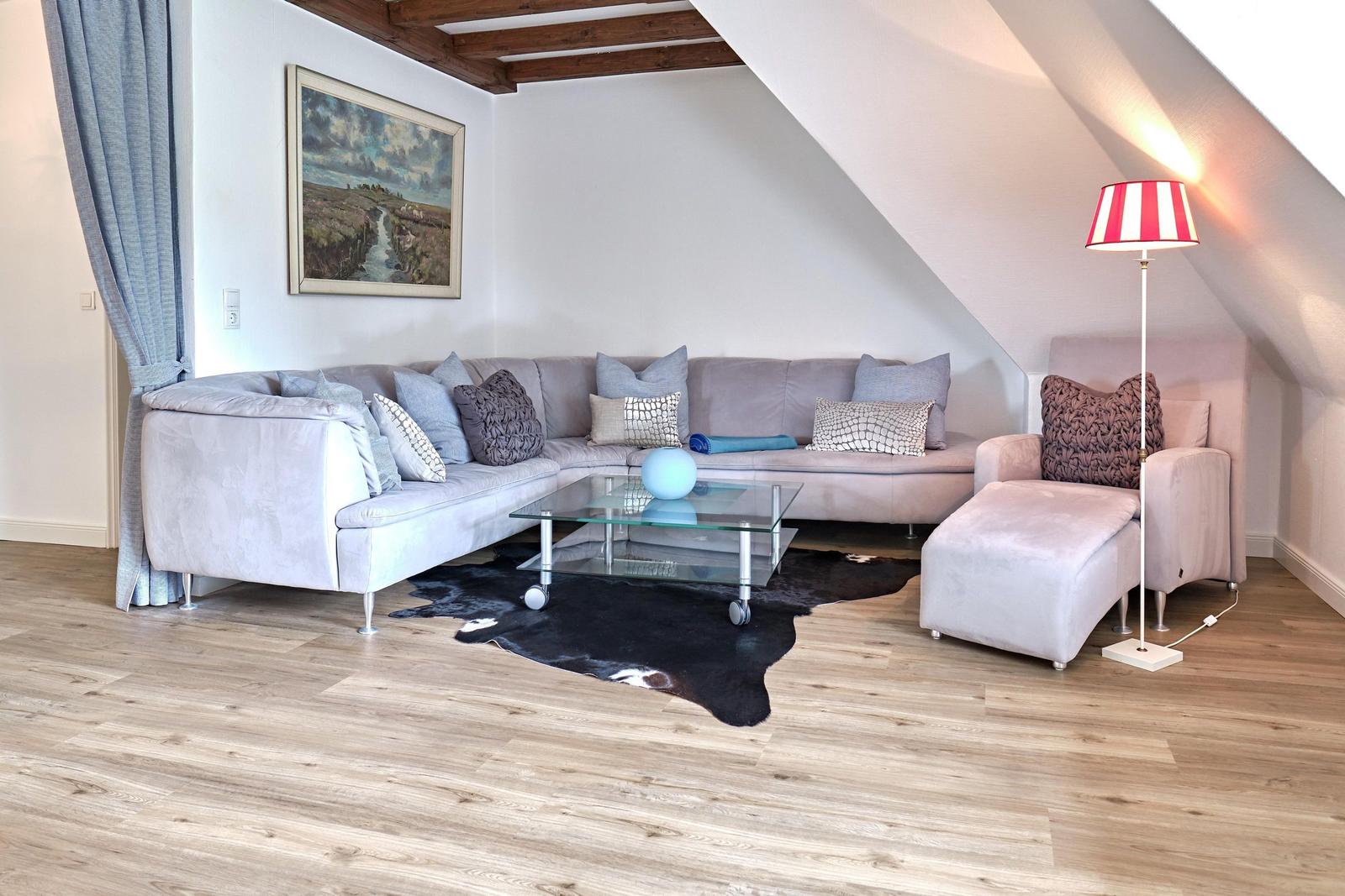 Wohnzimmer mit Sofa, Couchtisch und Stehlampe unter Dachschräge.
