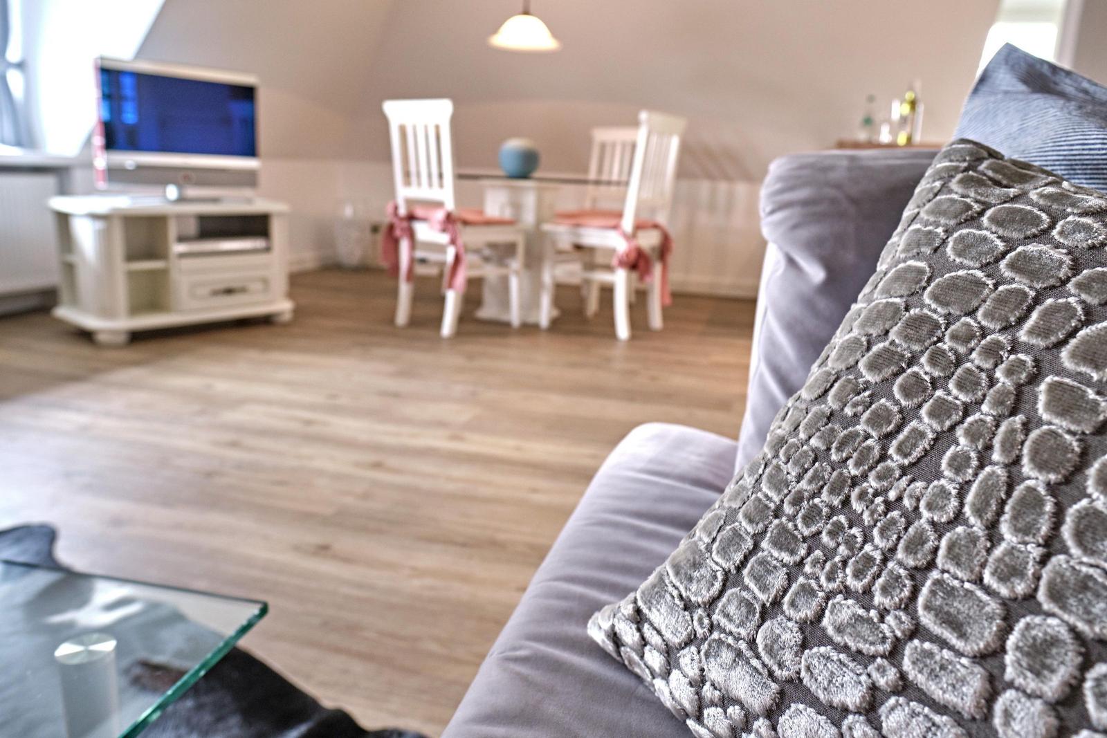 Wohnzimmer mit Sofa, Fernseher und Essbereich mit Tisch und Stühlen.