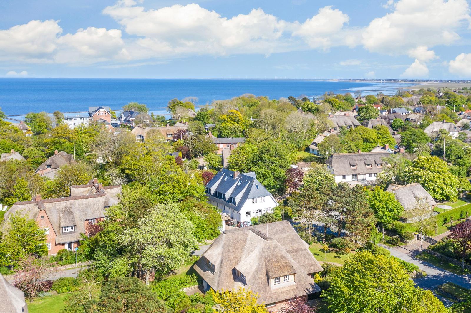 Village with thatched roofs and view of the sea.
