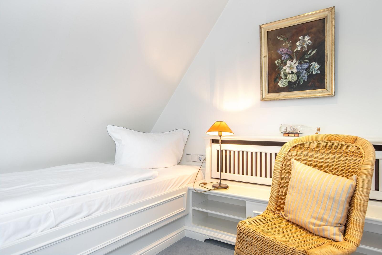 A bedroom with bed, chair, and wall painting.