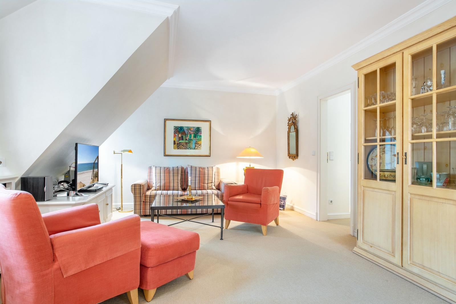 Living room with red armchairs, sofa, and glass cabinet.