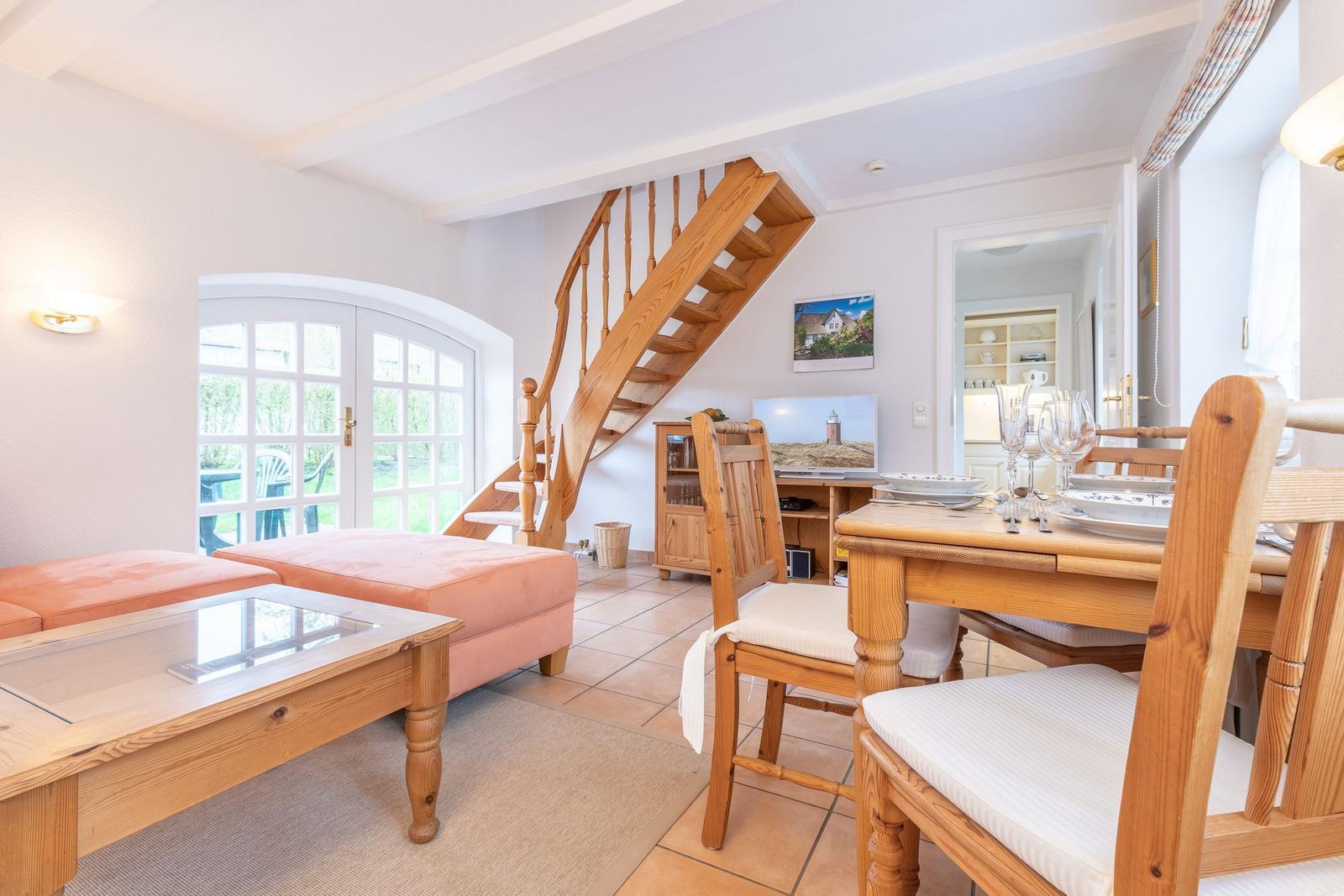 Wohn- und Essbereich mit Holztreppe und Glastür zum Garten