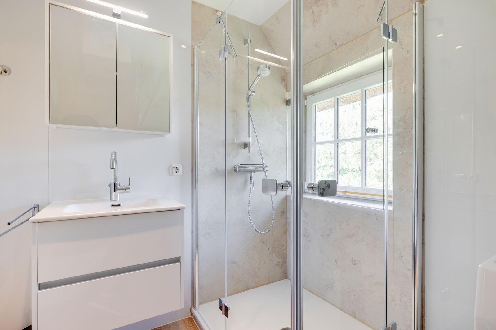 Dusche mit Glaswand, Waschbecken und Spiegelschrank