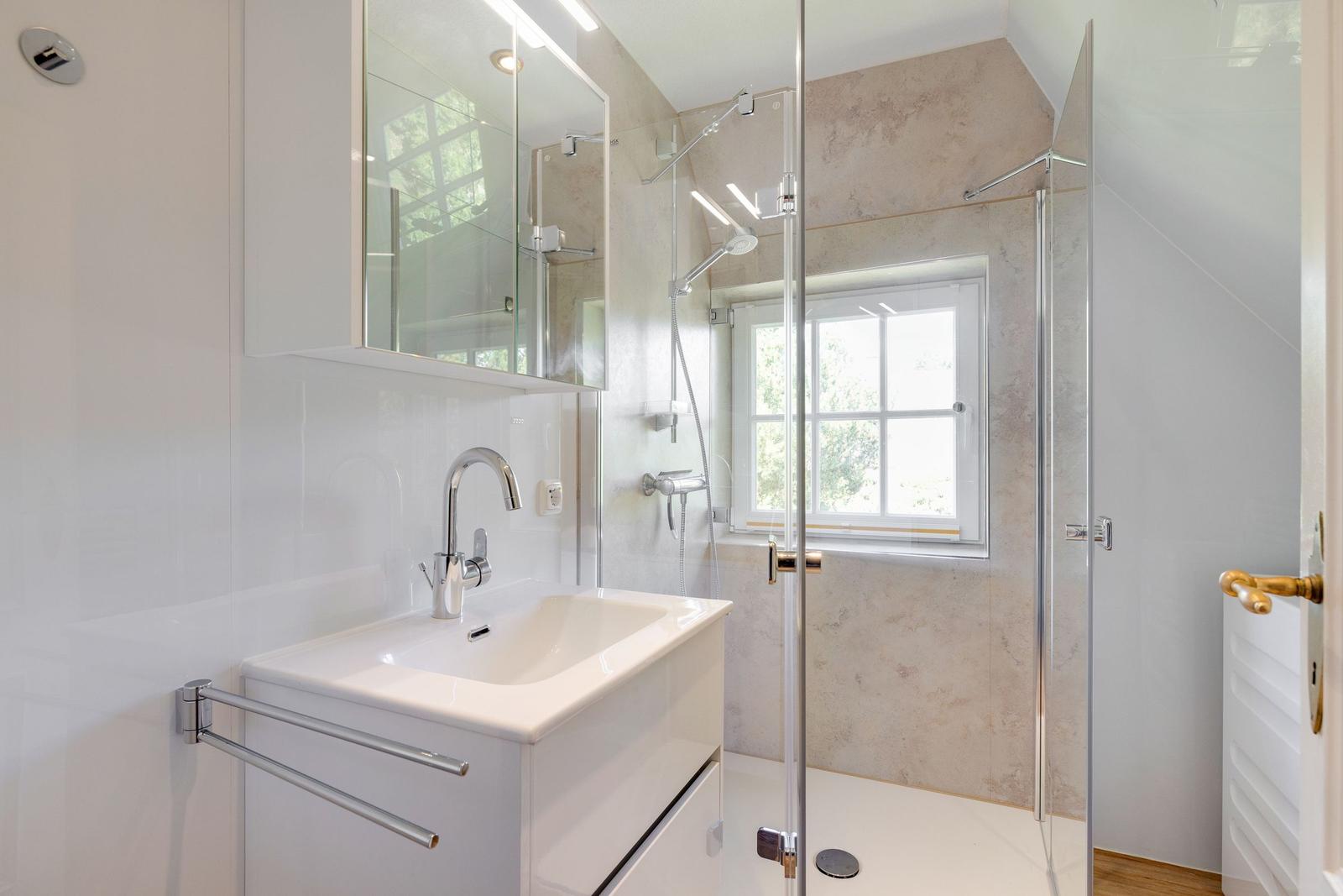 Badezimmer mit Dusche, Waschbecken und Fenster