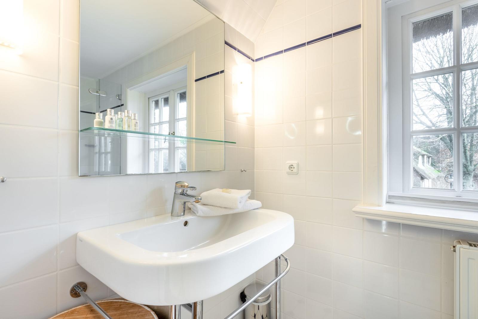 Bathroom with sink, mirror, and window.