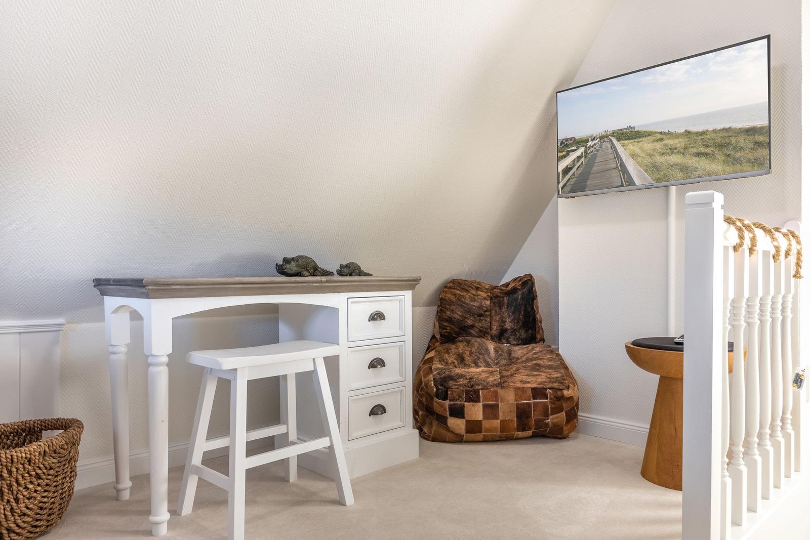 Bedroom with desk, armchair, and TV mounted on the wall.