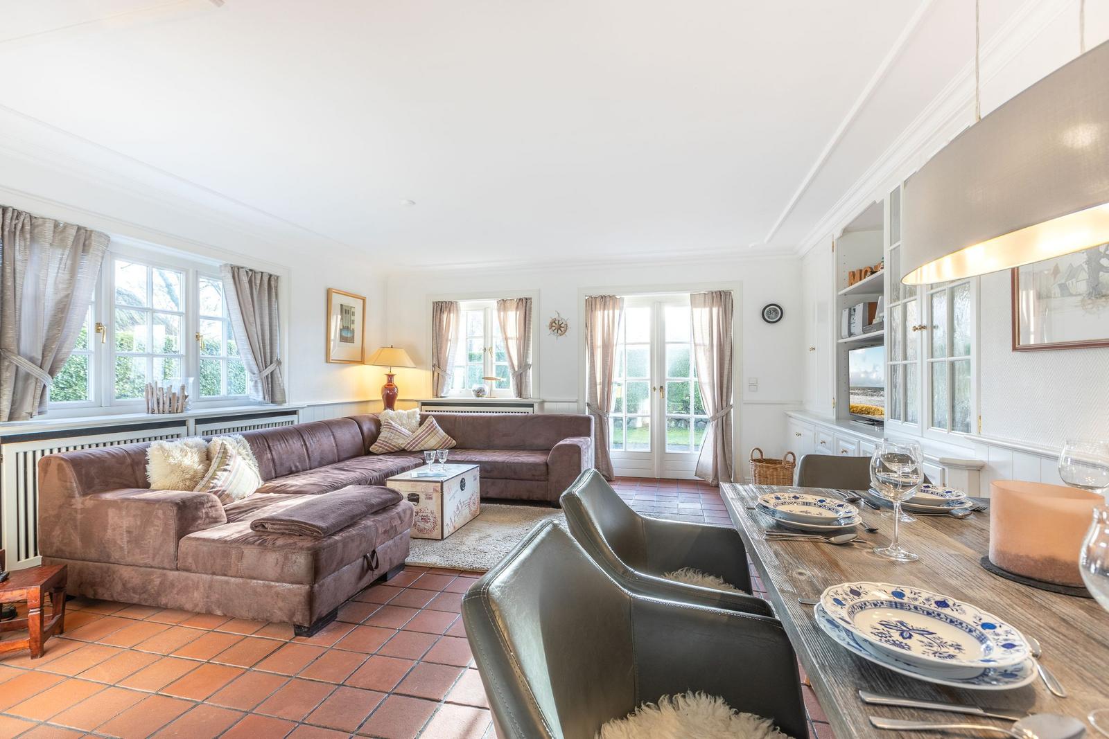 Living and dining area with sofa, table, and windows.