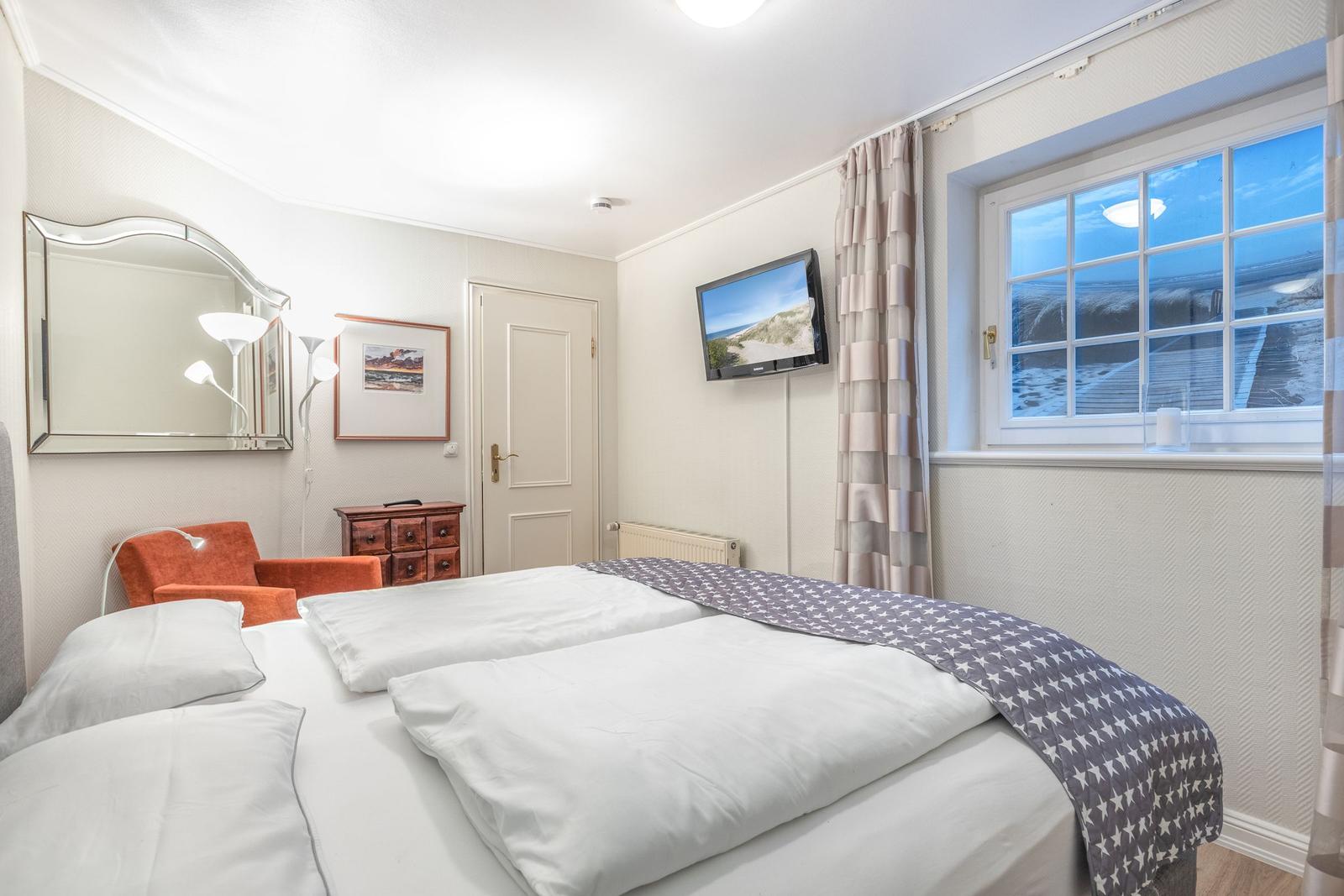Bedroom with double bed, window with sea view, and wall-mounted TV.