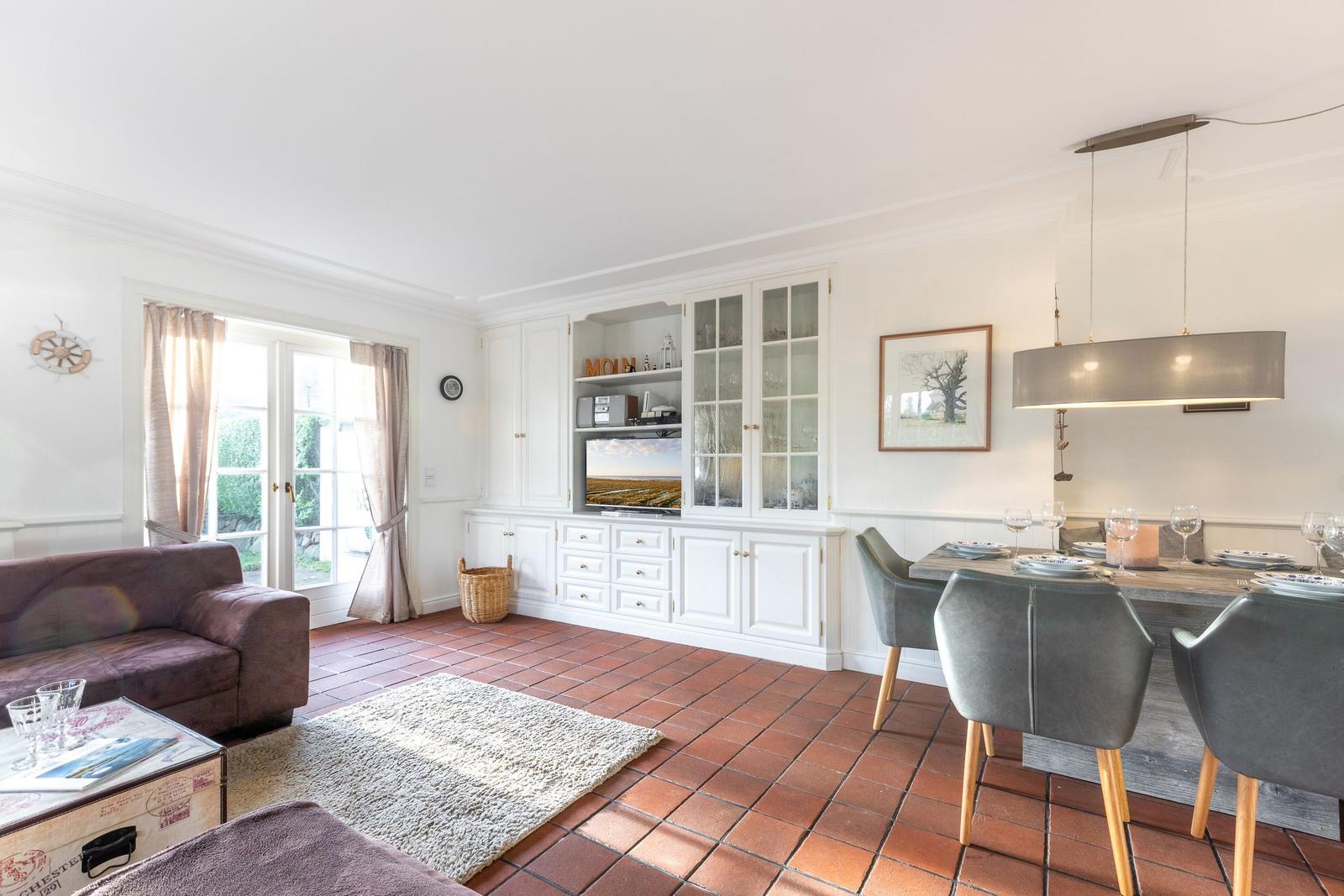 Living and dining area with dining table, sofa, TV, and terrace door.