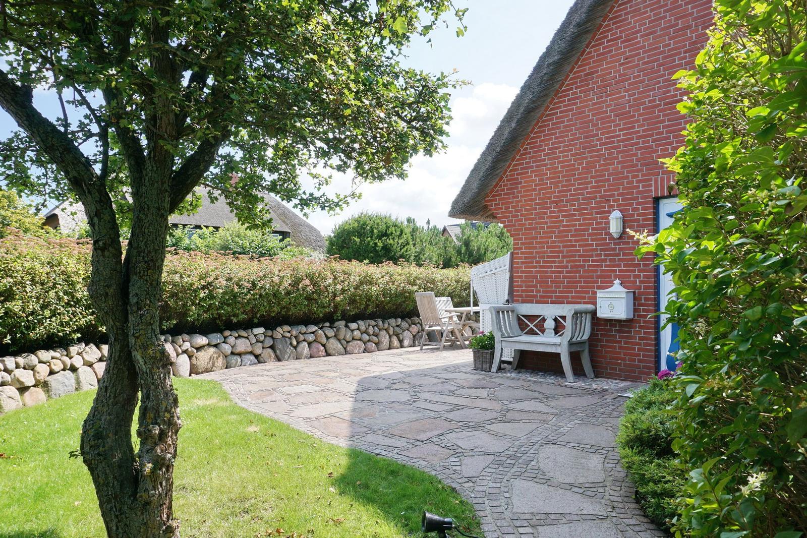 Red brick house with stone path and garden furniture.