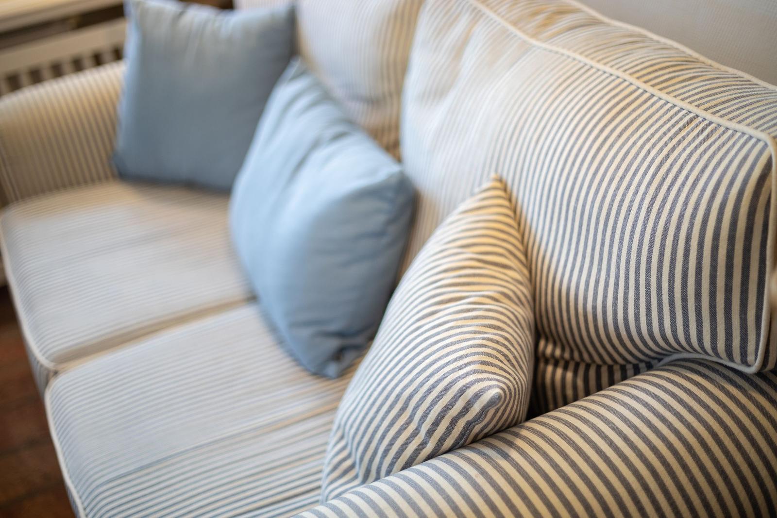 A sofa with striped upholstery and blue cushions.