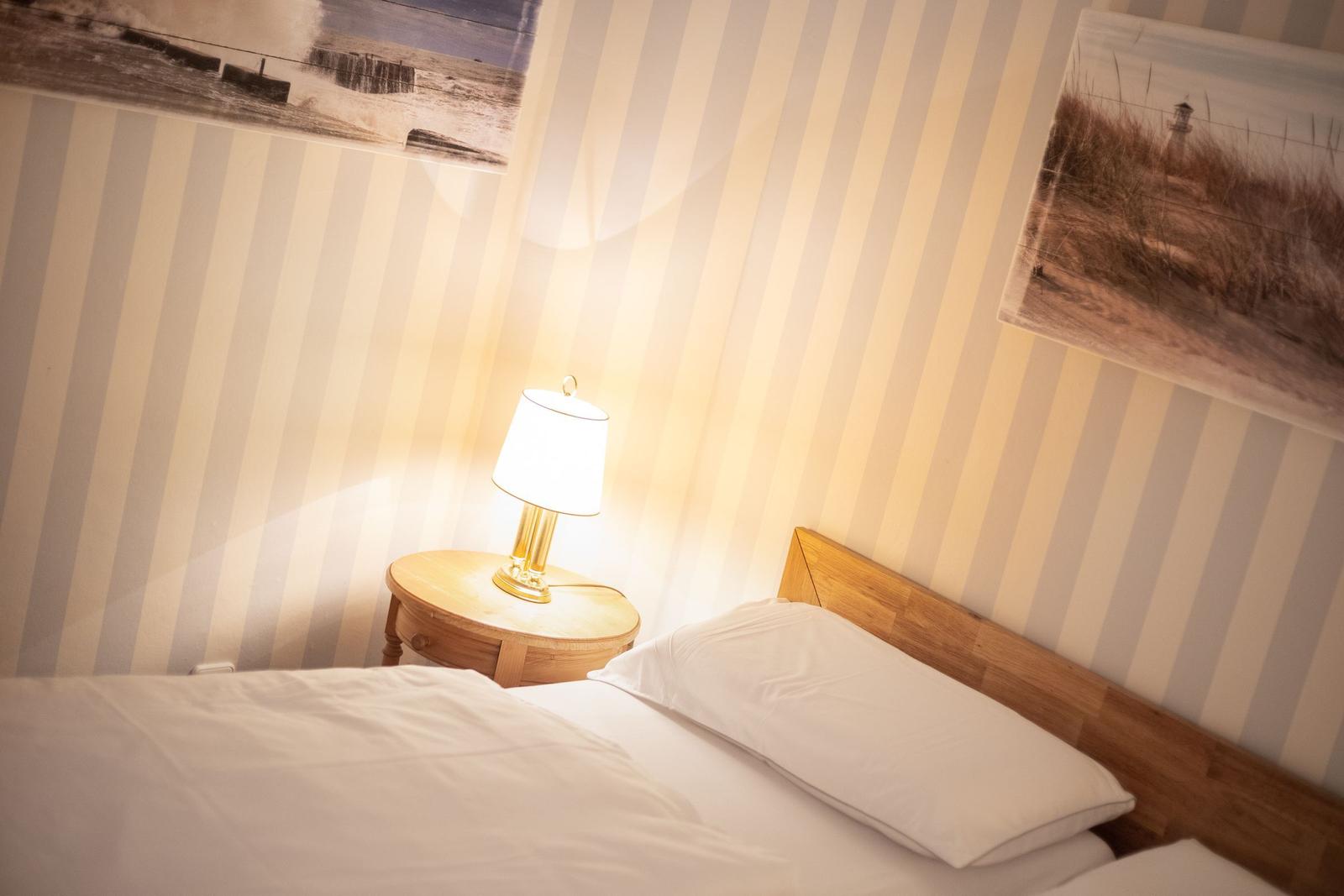 Bedroom with bed, nightstand, and lamp against striped wall