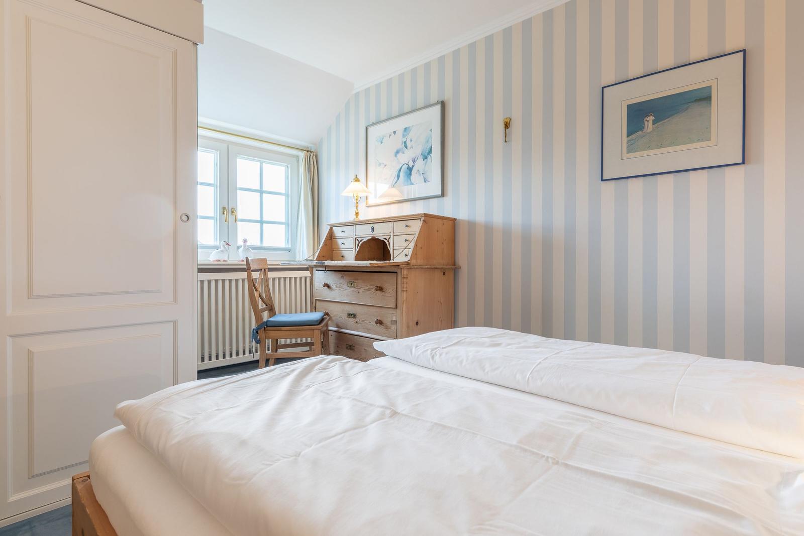 Bedroom with bed, desk, and striped wall.