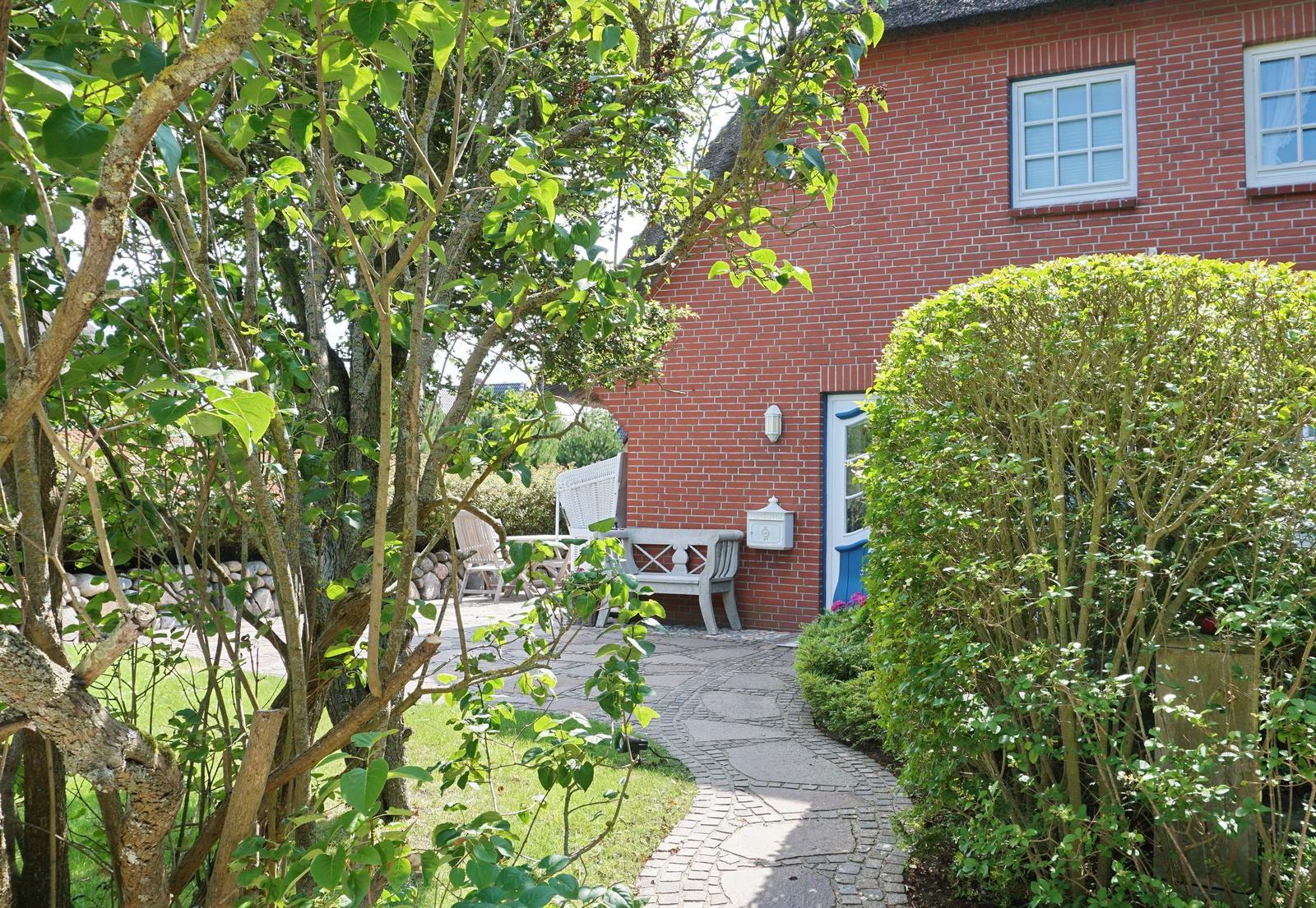 Red brick building with paved path and green surroundings.