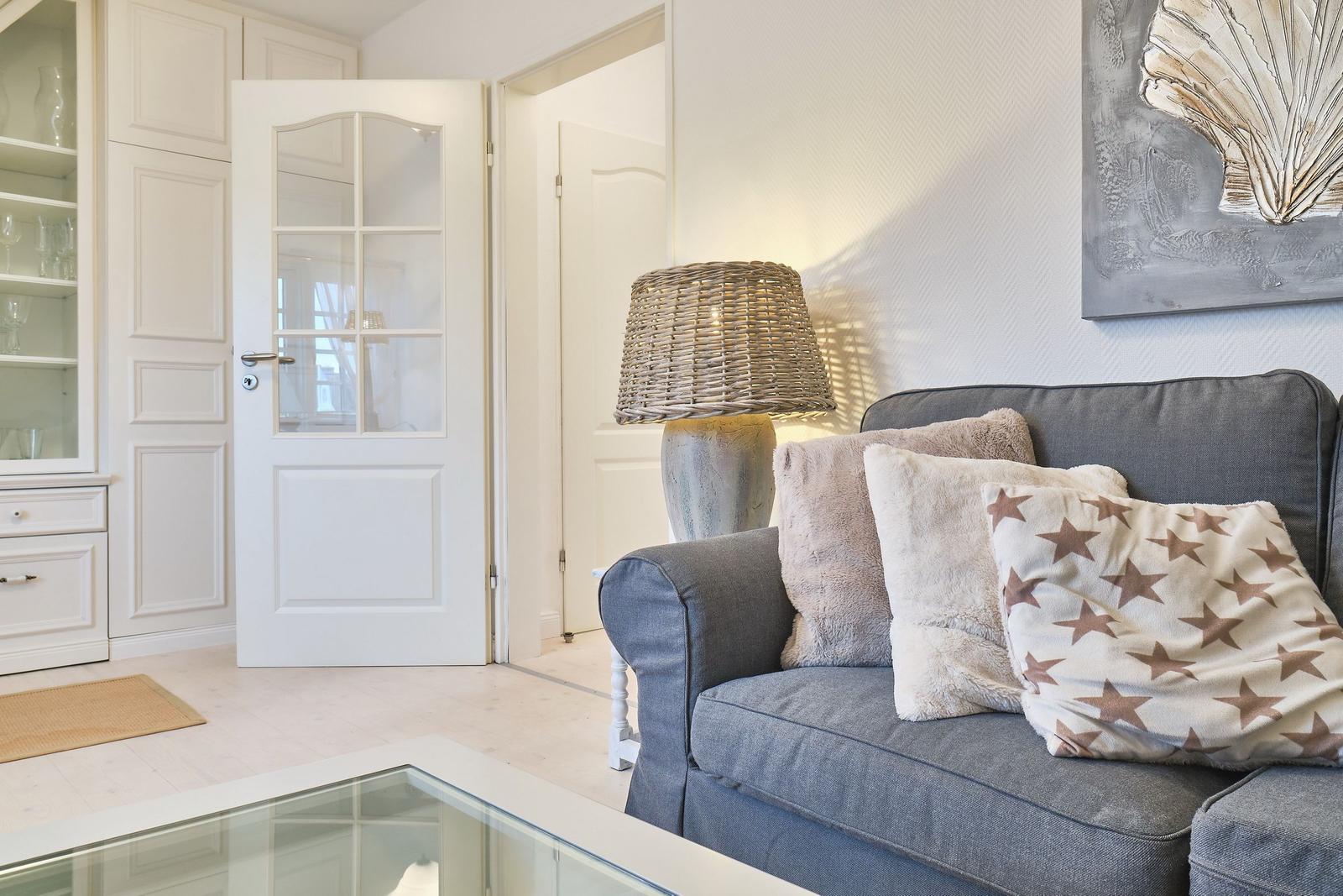 Ein Wohnzimmer mit grauem Sofa, Kissen und einer Lampe.