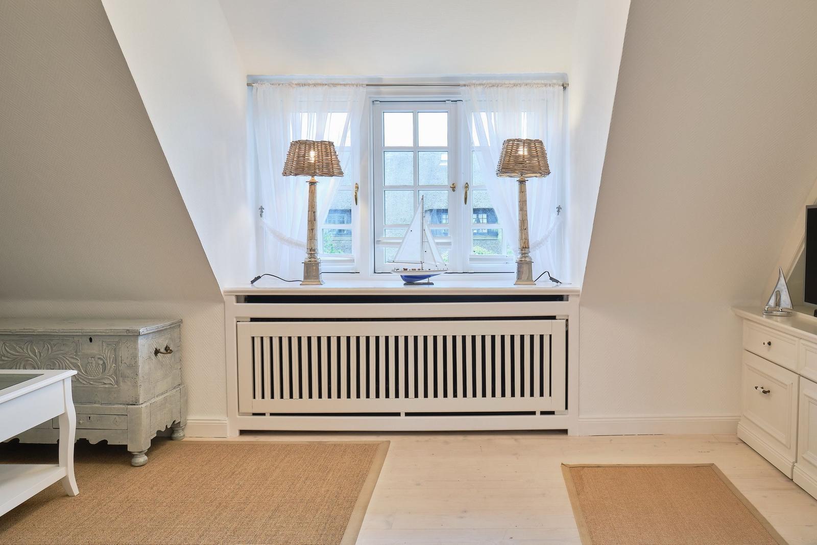 Dachgeschosszimmer mit Fenster, zwei Lampen und Modellboot.