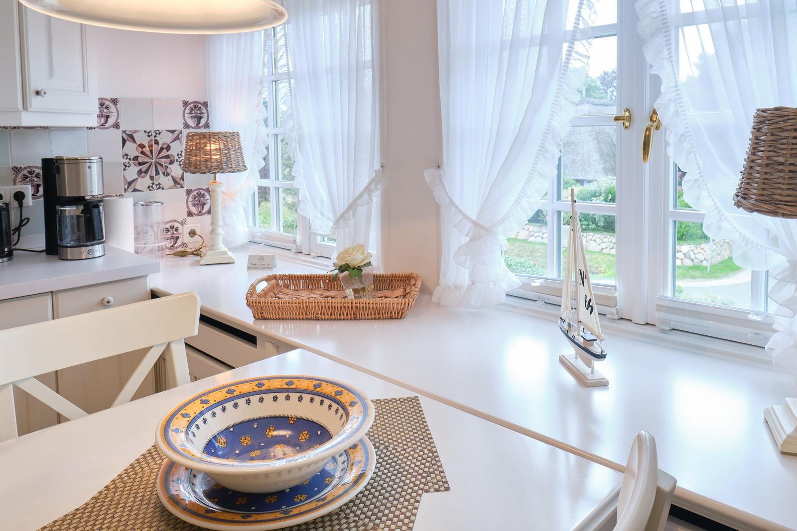 Küche mit weißem Tisch, blauer Schüssel und Blick auf Garten